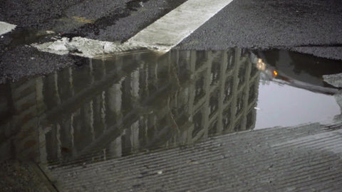 car driving reflection in dirty street puddle New York City