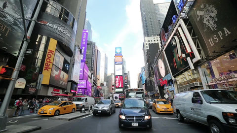 cars in Times Square traffic driving through crosswalk in wide shot