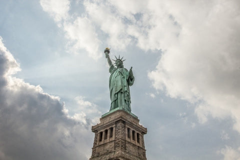 Statue of Liberty - long shot upward angle - beautiful bright day with blue sky and clouds - full view with base