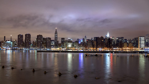 beautiful nighttime skyline timelapse of Manhattan skyscrapers with East River water reflections of lights in 4K