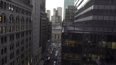 tilting down to cars in intersection below tall building in Midtown Manhattan NYC