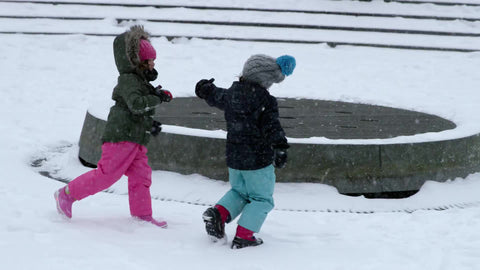 children running in winter blizzard snowstorm - kids holding hands playing in snow - snowing in Washington Square Park fountain slow motion