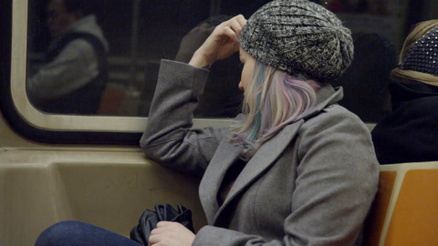 woman in hat sitting in seat riding subway - reflection in window from moving train in 4K NYC