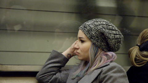pensive woman riding subway train - sitting with coat and hat in 4K NYC