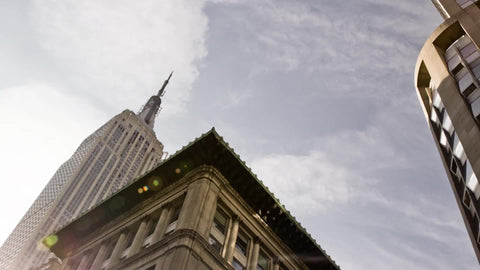 Empire State Building on bright sunny day - upward angle view driving down 5th Ave from street Midtown Manhattan