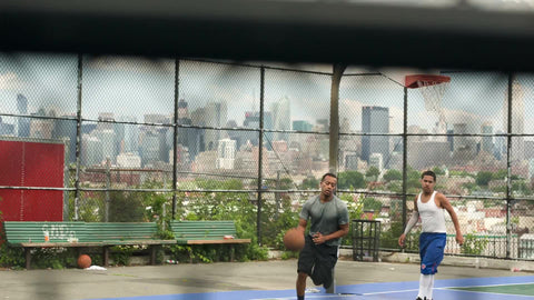pickup game on New Jersey basketball court with view of Manhattan skyline in NYC with Empire State Building seen through fence