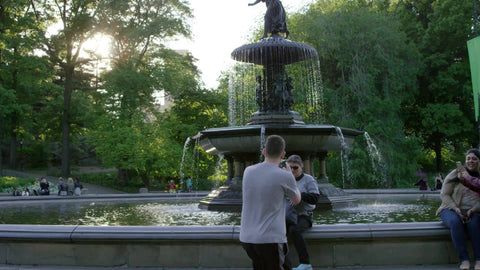 young man taking photograph of tourists, people with smartphone camera in Central Park in front of Bethesda statue