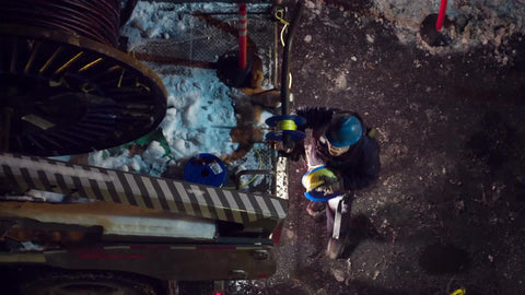 construction workers with hardhats and fiber optic cable spool at night - overhead view of NYC street in winter