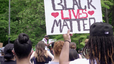 man holding Black Lives Matter sign with hearts at typically peaceful rally in New York City