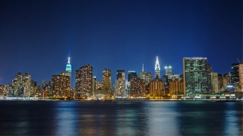 Manhattan skyline at night across East River water Empire State United Nations UN Chrysler Building skyscrapers lights NYC