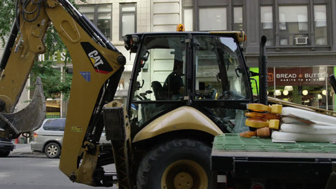 yellow construction shovel digger tractor driving down 5th Ave on sunny day in Manhattan NYC