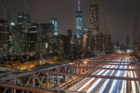 Brooklyn Bridge at night with fast cars traffic streaking lights at night Freedom Tower Manhattan buildings in background in New York City NYC