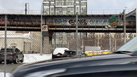 driving past graffiti elevated subway train track platform in Williamsburg Brooklyn New York City NYC