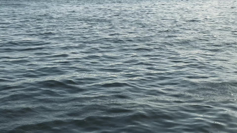 water waves in East River panning up to Brooklyn Bridge American flag Downtown Manhattan New York City NYC