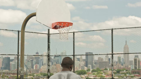 scoring jump shot off backboard on basketball court in summer with Empire State Building view through New Jersey fence