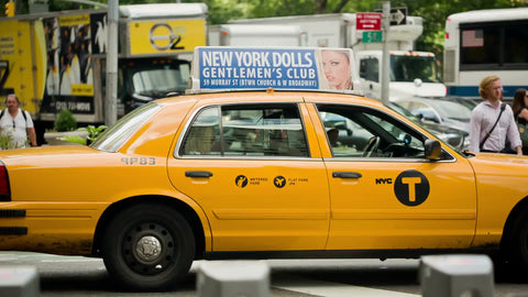 yellow taxi cab stopped at light in Manhattan traffic in summer on bright sunny day