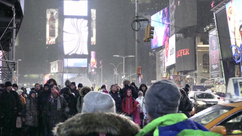 people waiting for taxis to cross - taxicabs driving across crosswalk in Times Square at night - snowing in Manhattan