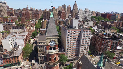 circling the Jefferson Market Library - aerial of landmark clock tower in Greenwich Village with Manhattan skyscrapers in background on sunny day