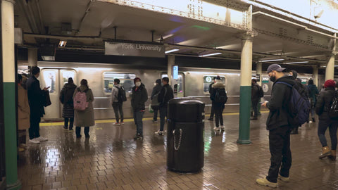 subway train running on track in platform passing passengers with masks New York City NYC