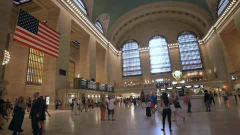 interior Grand Central Station in summer - big American flag in large terminal room with Metro North schedule information