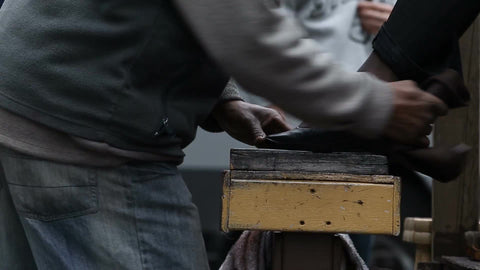 woman having shoes polished and cleaned on street by shoeshiner in NYC