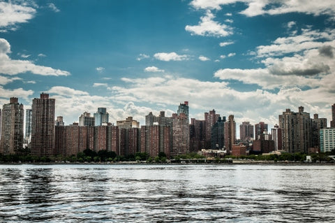 red brick buildings in Queens skyline across East River on bright sunny day, blue sky and clouds