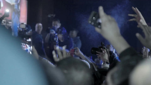 Havoc of Mobb Deep rapping on microphone on stage under bright lights at hip hop show in slow motion