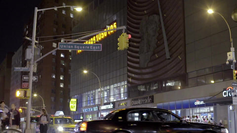 bicycle riding past numbers ticker and Union Square sign at night in NYC