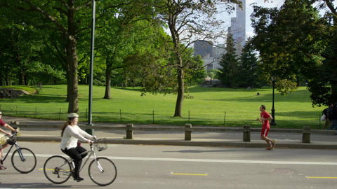 women on bicycles and man and woman jogging in Central Park on beautiful sunny summer day