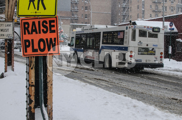 raise plow sign in winter - snowing in Manhattan - MTA bus driving on snow in winter - slush in street