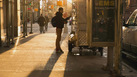 student paying street vendor for bag of food in early morning New York City