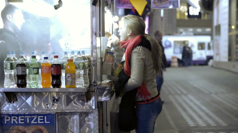 woman buying hot dog at food cart vendor on street at night in fall