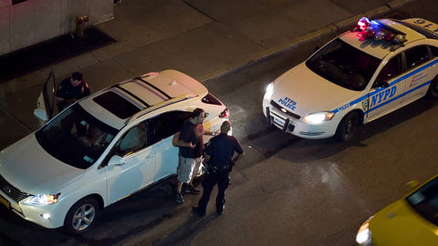 police officer talking to man at night - overhead view - flashing turret lights on cop car