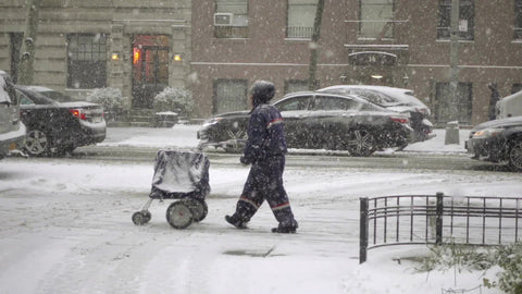 mailman pushing mail cart in street on snowing winter day in snow storm in NYC