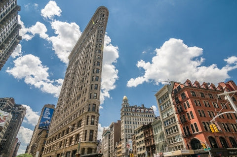 Flatiron Building on blue sky - medium shot of odd shaped flat landmark skyscraper on summer day