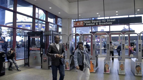 people entering Times Square subway station at night with turnstiles