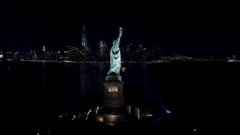 aerial Statue of Liberty circling at night from far with Manhattan skyline in background New York City NYC