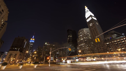Famous skyscrapers from Union Square Park - Empire State Building and clock tower with cars in traffic - light streaks at night in Manhattan NYC