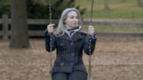 woman with coat and scarf on swing, swinging in fall autumn cold Central Park swings