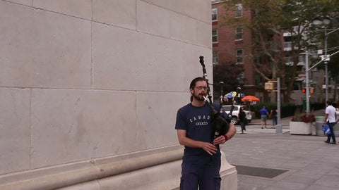 man playing bagpipes in Washington Square Park on summer day