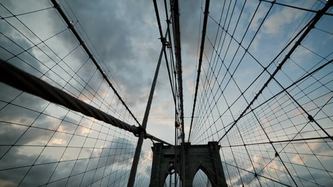 tilting down to people crossing Brooklyn Bridge at beautiful sunset in NYC