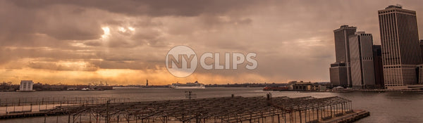 wide shot of East River at sunset with Statue of Liberty in distance - orange sky in early evening