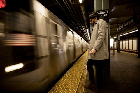 man leaning on column in Bedford Ave subway station New York City
