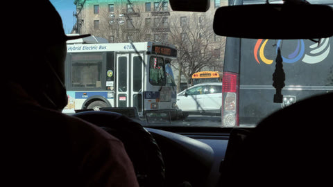 Uber driver with medical mask - taxi in covid winter - cab windshield in Harlem - yellow school bus New York City NYC