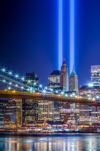 September 11th beams over skyscrapers in Manhattan from across East River water at night