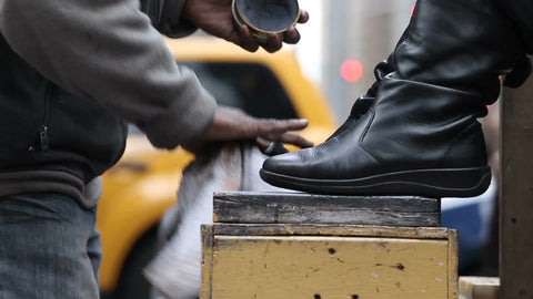 man shining woman's boots on street - shoeshiner polishing shoes in NYC