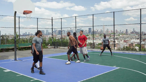 kid scoring alley-oop in basketball on summer day on outdoor court - kids playing with view of Manhattan skyline