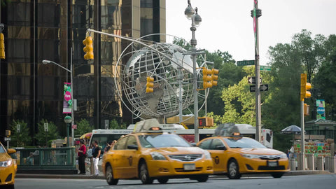 taxi cabs driving in traffic at Columbus Circle with steel globe sculpture on summer day in Manhattan NYC