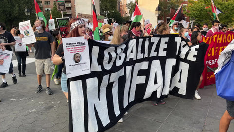 protestors marching with Globalize the Intifada sign at Palestinian rights protest - Empire State Building in background - activists in New York City NYC