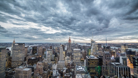 Empire State Building and Manhattan skyscrapers from high view with cold blue clouds overhead in early evening